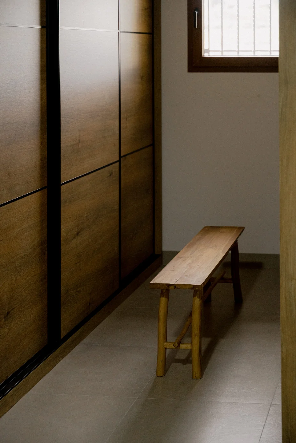 Banco de madera de teca Raw utilizado como descalzador en pasillo o vestidor moderno